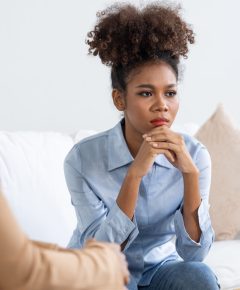 Sad PTSD woman patient in crucial therapy for mental health with psychologist, depression or grief after life failure. Frustrated trauma young woman talking to a psychologist about emotion in clinic